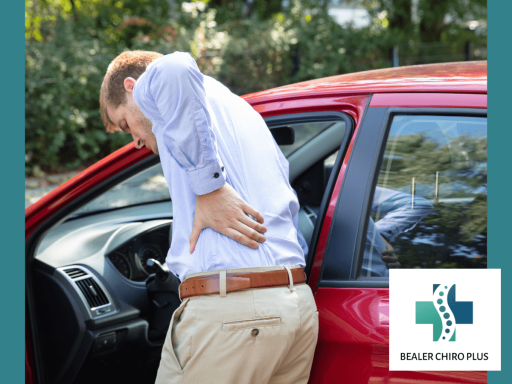 man with back pain standing by car